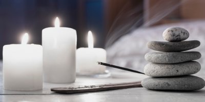 Vonná tyčinka, zapálené svíčky a kameny