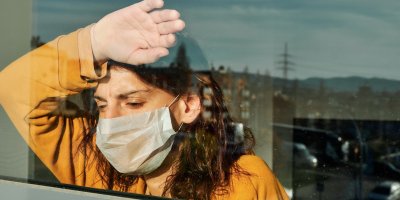 Žena s ústenkou pozorující dění za oknem 