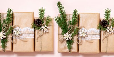 Dárky zabalené v přírodním papíru jsou omotané krajkou a ozdobené větvičkami jehličnanu, šiškami, provázkem a dřevěnými ozdobami