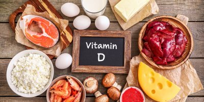 Vitamin D napsaný na tabulce a kolem potraviny, které ho obsahují