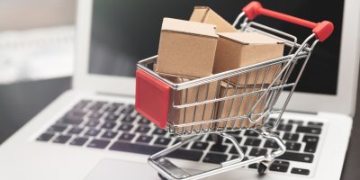 Malý nákupní košík naplněný papírovými krabičkami stojí na notebooku