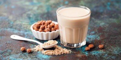 Pohled na sladké rostlinné mléko ve sklenici, v pozadí tygří ořechy