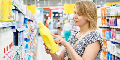 Žena si v obchodě prohlíží čisticí prostředek