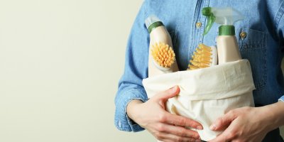 Muž nese čisticí prostředky a kartáče v látkové tašce