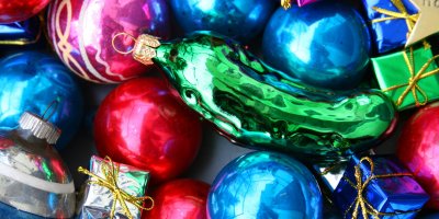 Barevné vánoční koule a mezi nimi zářivě zelená ozdoba kyselé okurky