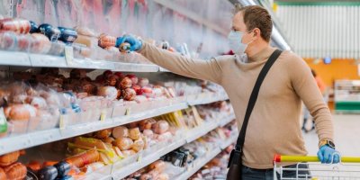 Muž v roušce a rukavicích nakupuje salámy 