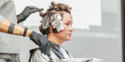 Kadeřnice barví ženě vlasy za pomoci alobalu