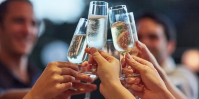 Lidé si přiťukávají sklenicemi šumivého vína