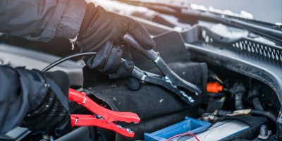 Muž startuje auto pomocí startovacích kabelů