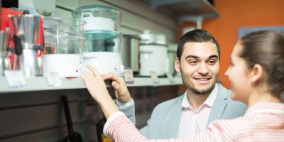 Žena a muž jsou v obchodě a dívají se na vystavené parní hrnce