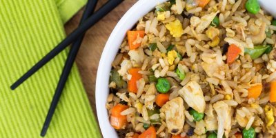 Rýže s kuřetem a zeleninou v misce, vedle čínské hůlky