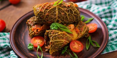 Kapustové rolky, nakrájená cherry rajčata a bylinky na talíři