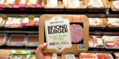 Žena drží v supermarketu vegetariánské hamburgery od Beyond Meat