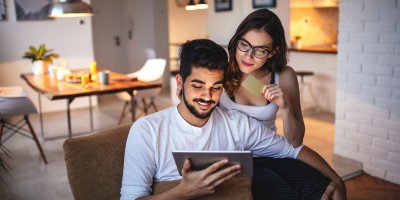 Muž a žena si prohlížejí tablet, žena drží platební kartu
