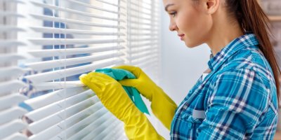 Žena čistí lamely žaluzií hadříkem