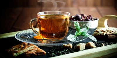 Skleněný hrneček s černým čajem na podnosu