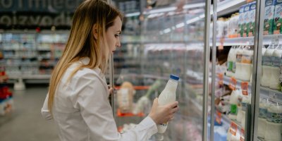 Žena si vybírá mléko z regálu