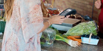 Žena platí kartou v obchodě se zeleninou a ovocem