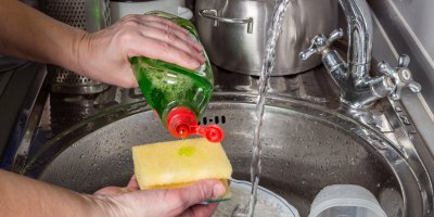 Člověk si dávkuje prostředek na nádobí na houbičku