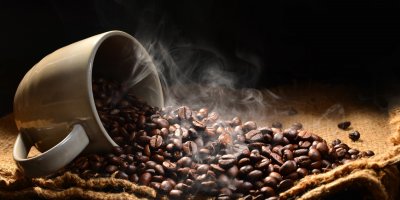 Horká kávová zrna a prázdný šálek