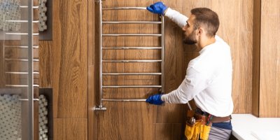 Muž instaluje otopný žebřík v koupelně