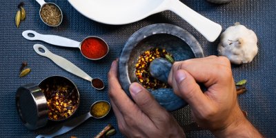 Mužské ruce drtí směs koření v hmoždíři