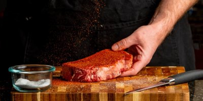 Muž koření maso červenou směsí koření