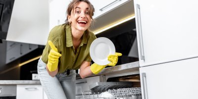 Žena v rukavicích naplňuje myčku