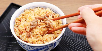 Detail na misku s rýží, kterou kdosi nabírá hůlkami