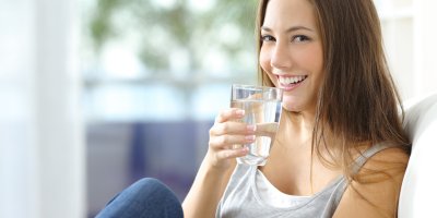 Usmívající se žena drží sklenici s vodou