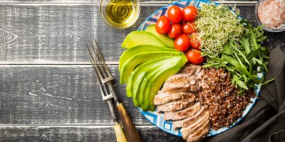 Talíř, na kterém je avokádo, cherry rajčata, výhonky, kuře, rukola, quinoa