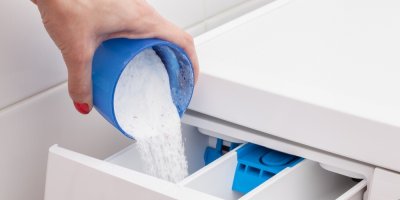 Žena sype prací prášek do pračky