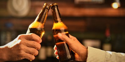 Pár si přiťukává skleněnými lahvemi s pivem