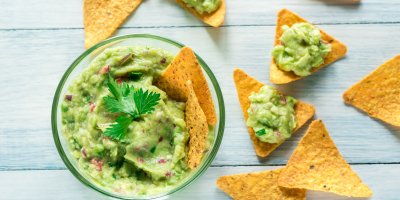 Guacamole ozdobené koriandrem v misce, tortilla chipsy