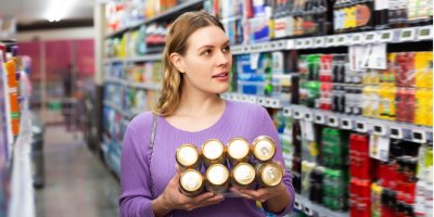 Mladá žena kupuje hromadu plechovek s pivem