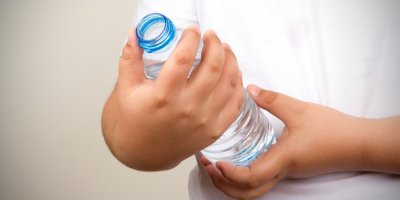 Člověk drží PET lahev s vodou