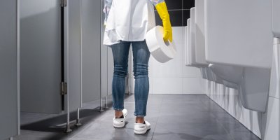 Uklízečka nese na toalety roli toaletního papíru