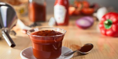 Kečup ve skleněné dóze a za ním kečup v lahvi Heinz