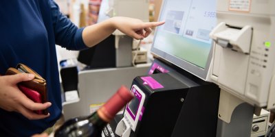 Člověk kupuje láhev alkoholu na samoobslužné pokladně
