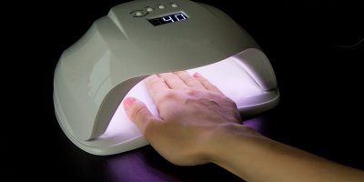 Ruka s růžově nalakovanými nehty v UV lampě