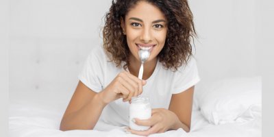 Žena jí bílý jogurt v posteli