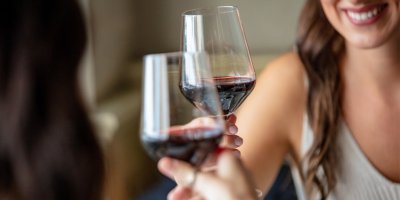 Dvě ženy si připíjí červeným vínem