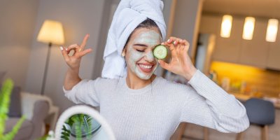 Žena s maskou na obličeji drží v ruce okurku