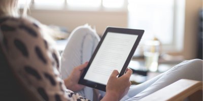 Žena si čte v křesle z čtečky knih