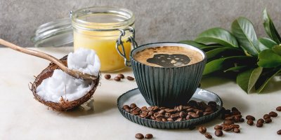 Káva v hrnku a kolem kávová zrna, máslo a sůl