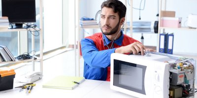 Muž poslouchá stetoskopem mikrovlnku