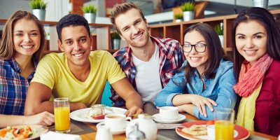 Parta přátel sedí v kavárně a dávají si snídaňové menu