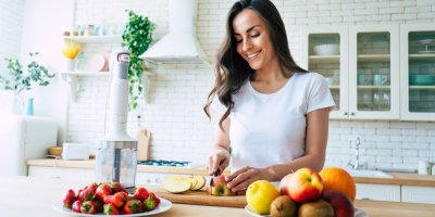 Usměvavá, spokojeně a zdravě vyhlížející žena krájí ovoce