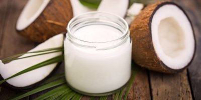 Ztuhlý kokosový olej ve skleničce a rozpůlený kokosový ořech