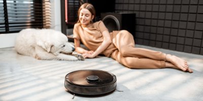 Žena si hraje se psem a kolem jezdí robotický vysavač